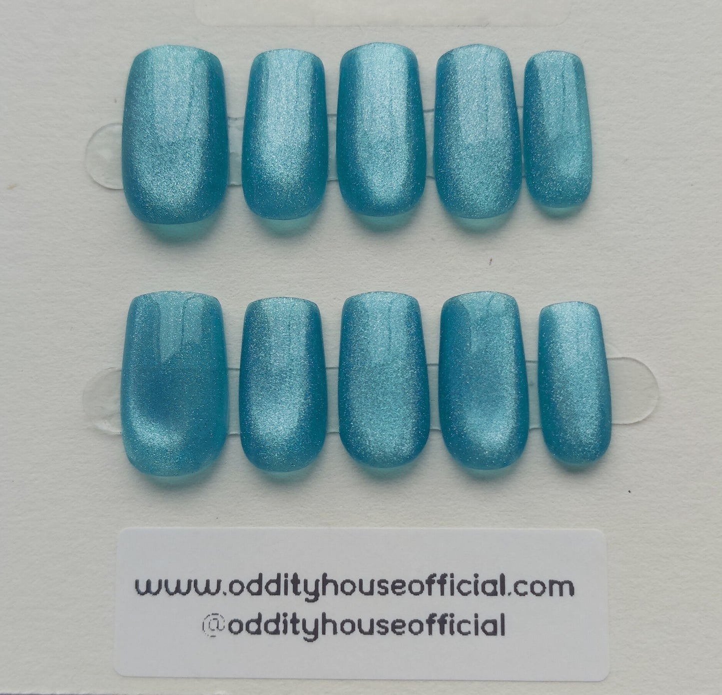 Set of blue glittery press-on nails on a clear backing card with branding information - oddityhouseofficial.com